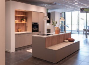 Design keuken met kookeiland met bankje en open nis als koffiehoekje in macchiato beige en hout kleur