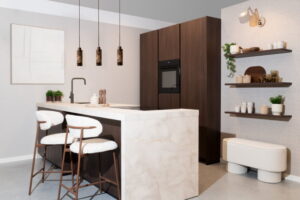 Modern schiereiland met bar – notenhout eiland en hoge kasten met doorlopend beige marmerlook werkblad Modern schiereiland met bar – notenhout eiland en hoge kasten met doorlopend beige marmerlook werkblad