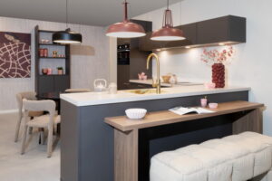 Grijze moderne L-keuken met bar en bankje met burgundy-roze lampen en accessoires