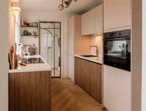 Moderne parallel keuken in Japandi stijl met notenhouten en beige frontjes, BORA kookplaat en wijnklimaatkast - gezellige binnenkijker keuken van trotse I-KOOK klant uit Tilburg Moderne parallel keuken in Japandi stijl met notenhouten en beige frontjes, BORA kookplaat en wijnklimaatkast - gezellige binnenkijker keuken van trotse I-KOOK klant uit Tilburg