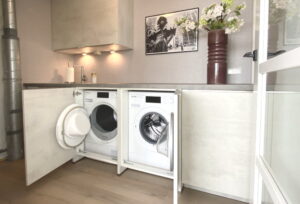 Droger en wasmachine achter deur in keukenkast en onder een werkblad in de (bij)keuken Droger en wasmachine achter deur in keukenkast en onder een werkblad in de (bij)keuken