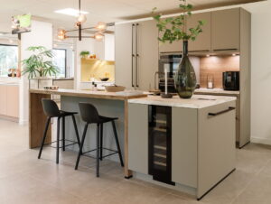 Greige modern kookeiland met bar en coffee corner in houten nis met LED verlichting. Greige modern kookeiland met bar en coffee corner in houten nis met LED verlichting.