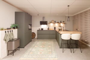 Groene moderne keuken met schiereiland en zwarte hanglamp boven de houten bar