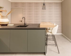 KEUKENTRENDS 2026 - Greeploze groene keuken met eikenhout ontbijtbar en 2 comfortabele barkrukken - donkergrijs natuursteenlook Greengridz keukenblad en Gun Metal zwarte kraan en spoelbak KEUKENTRENDS 2026 - Greeploze groene keuken met eikenhout ontbijtbar en 2 comfortabele barkrukken - donkergrijs natuursteenlook Greengridz keukenblad en Gun Metal zwarte kraan en spoelbak