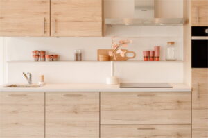 Japandi keuken organische vormen met lichthout keukenfrontjes en wit aanrechtblad + achterwand, keukenaccessoires in glas, RVS en pastel kleuren perzik, oranje en hagelwit - Keukentrends 2026
