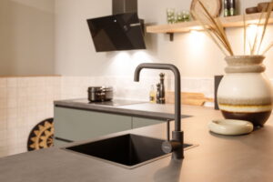 Groene Mid Century Modern keuken vintage look met zwarte keukenkraan en spoelbak, inductiekookplaat en wand afzuigkap