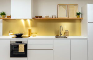 Greeploze witte keuken met wit blad en goudkleurige achterwand