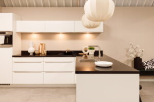 Strakke witte keuken met zwart blad - witte L-keuken met bar