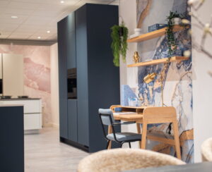 Keukentrends 2027: keukenzones - Moderne blauwe keuken werkzone = licht eiken bureau en wandplanken als werkplek